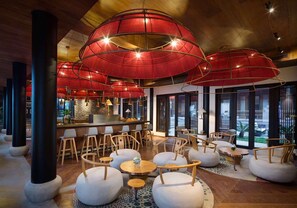 A modern bar area with round tables and chairs, a counter with a barista, and large red umbrellas overhead. - Blossom Hill Hotel Ningbo Hanling (Ningbo)