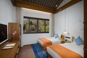 A hotel room with two beds, a wooden desk, a TV, and a large window with a view of trees. - Blossom Hill Hotel Ningbo Hanling (Ningbo)