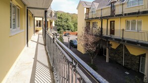 A yellow building with balconies, a covered walkway, and a parking area. - 2 Garnish Court (Glengarriff)