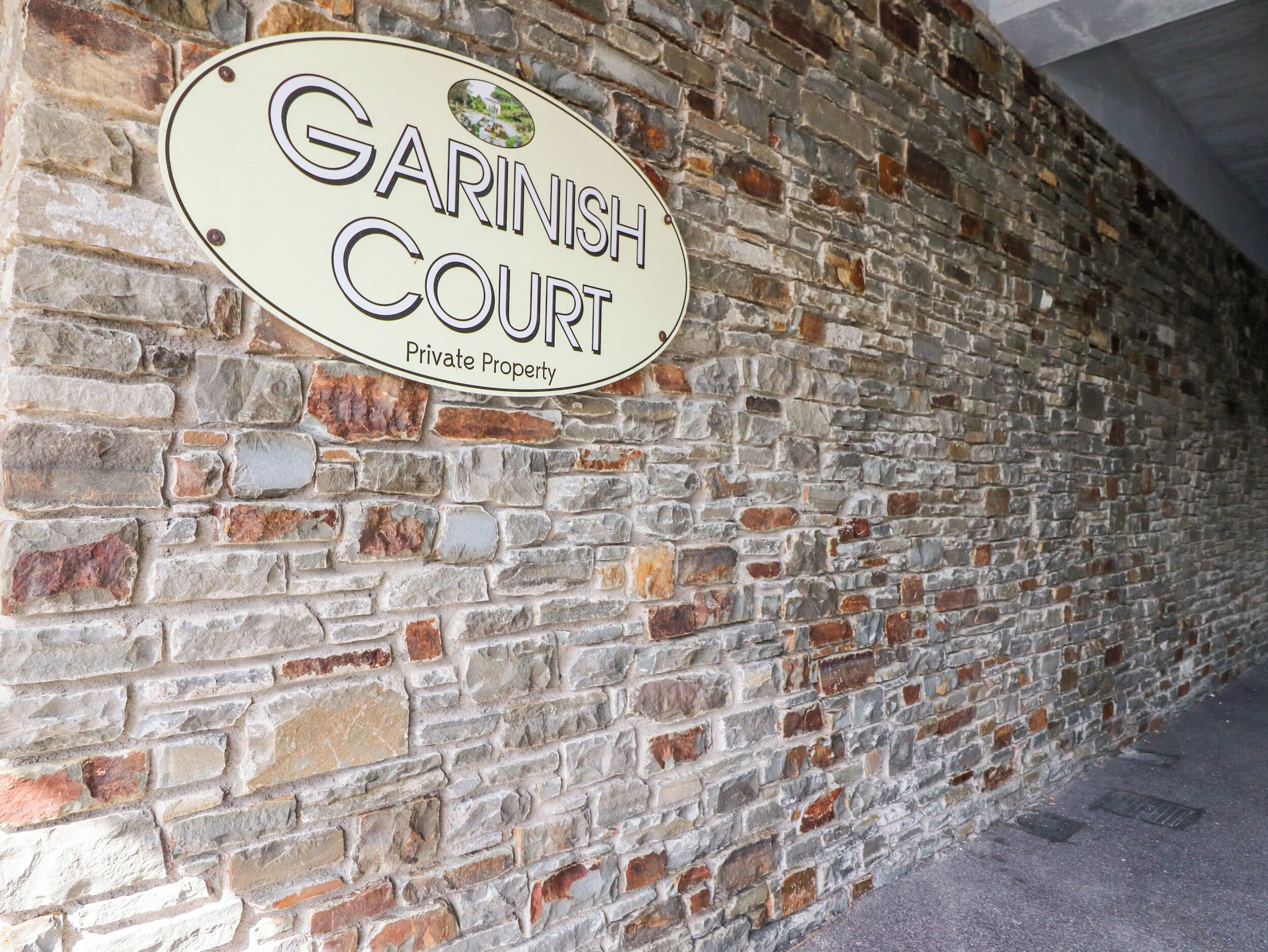 A brick wall with a sign that reads "Garinish Court Private Property."