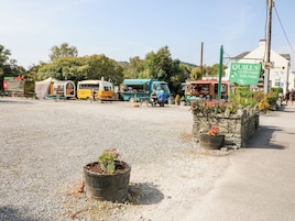 Una carretera con camiones de comida, un cartel de Estacionamiento para Clientes de Quill, y una jardinera de piedra con flores.