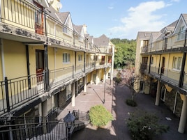Un patio con edificios amarillos, balcones y un camino central.
