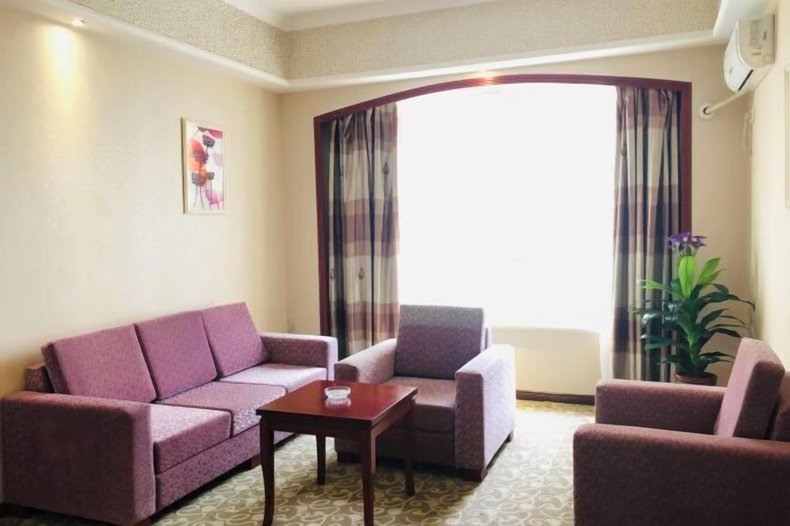 A hotel room with a sofa set, a small table, and a potted plant.