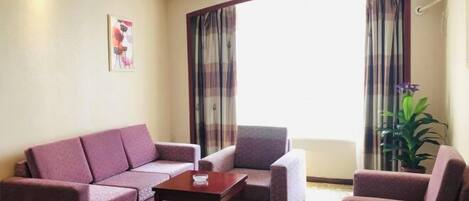 A hotel room with a sofa set, a small table, and a potted plant.