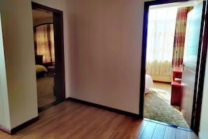 A hotel room with a wooden floor, a bed with a white bedspread, and a window with curtains. - Yongheng Business Hotel (Debao)