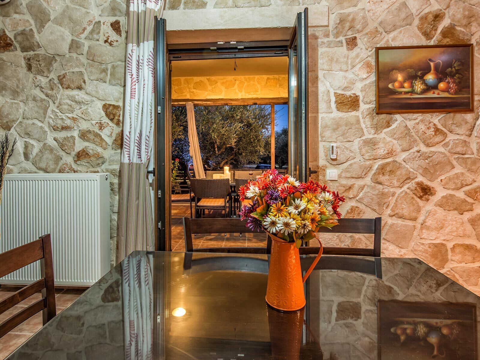 A dining area with a glass table, chairs, and a vase of flowers.