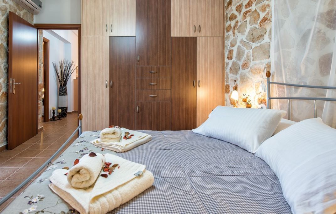 Ein Hotelzimmer mit einem Bett, einem Schrank, einem Spiegel und einer Steinwand.