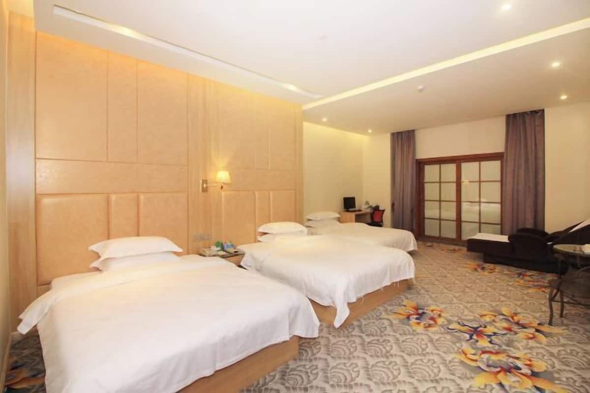 A hotel room with two beds, a sofa, a desk, and a piano.