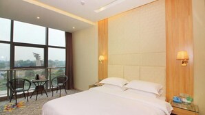 A hotel room with a large bed, two bedside tables, a window with a view, and a balcony with chairs. - Dongfang Shuiyun Spa Hotel (Qingyuan)
