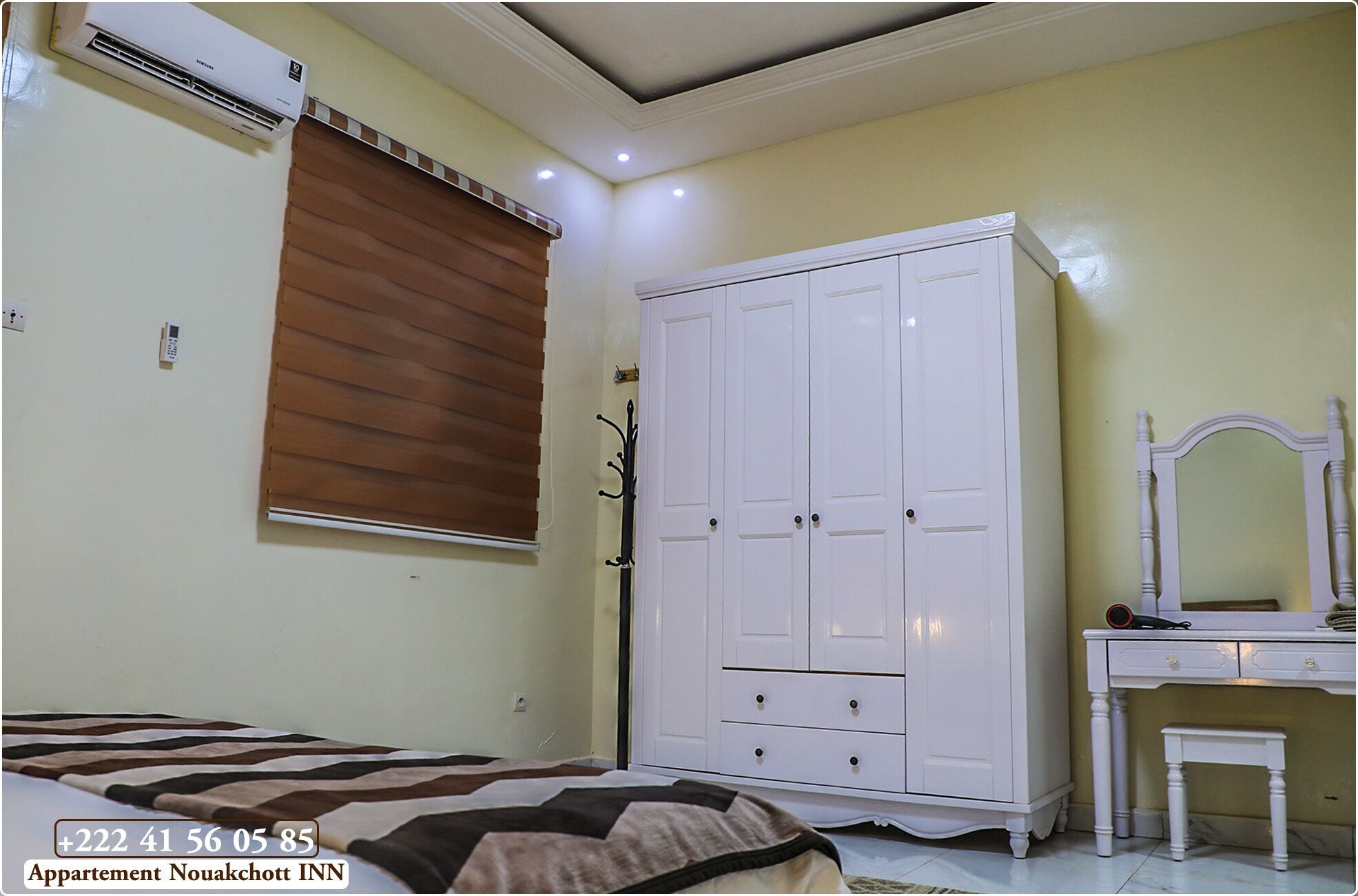 A bedroom with a bed, a wardrobe, a bedside table, and a mirror.