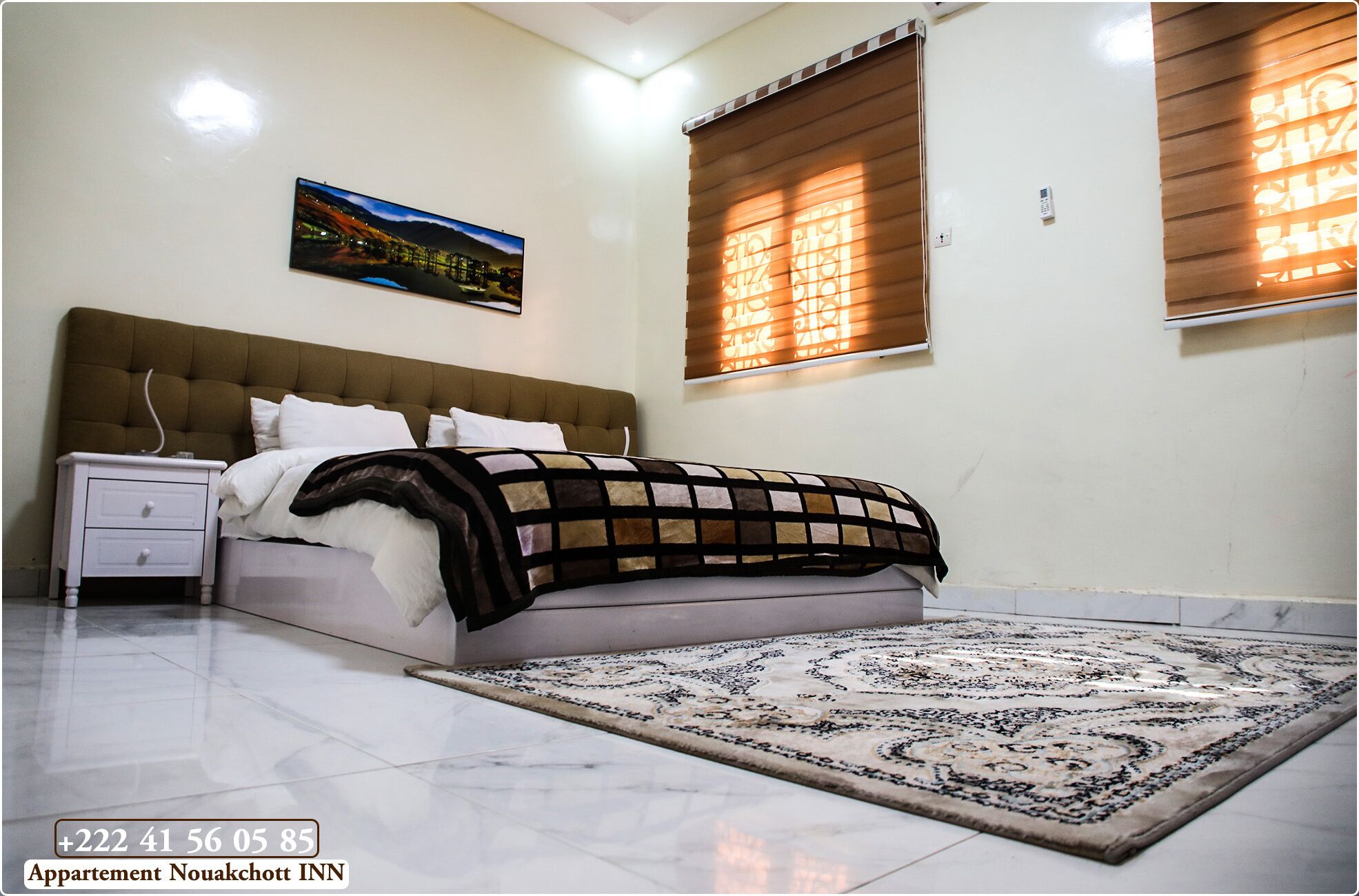 A bedroom with a bed, nightstand, and a large rug.