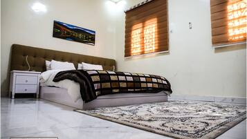A bedroom with a bed, nightstand, and a large rug.