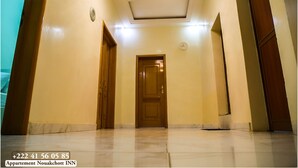 A hallway with a wooden door, a clock, and a phone number.