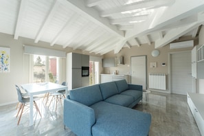 A modern kitchen with white cabinets, a built-in oven, and a dining area with a white table and chairs.