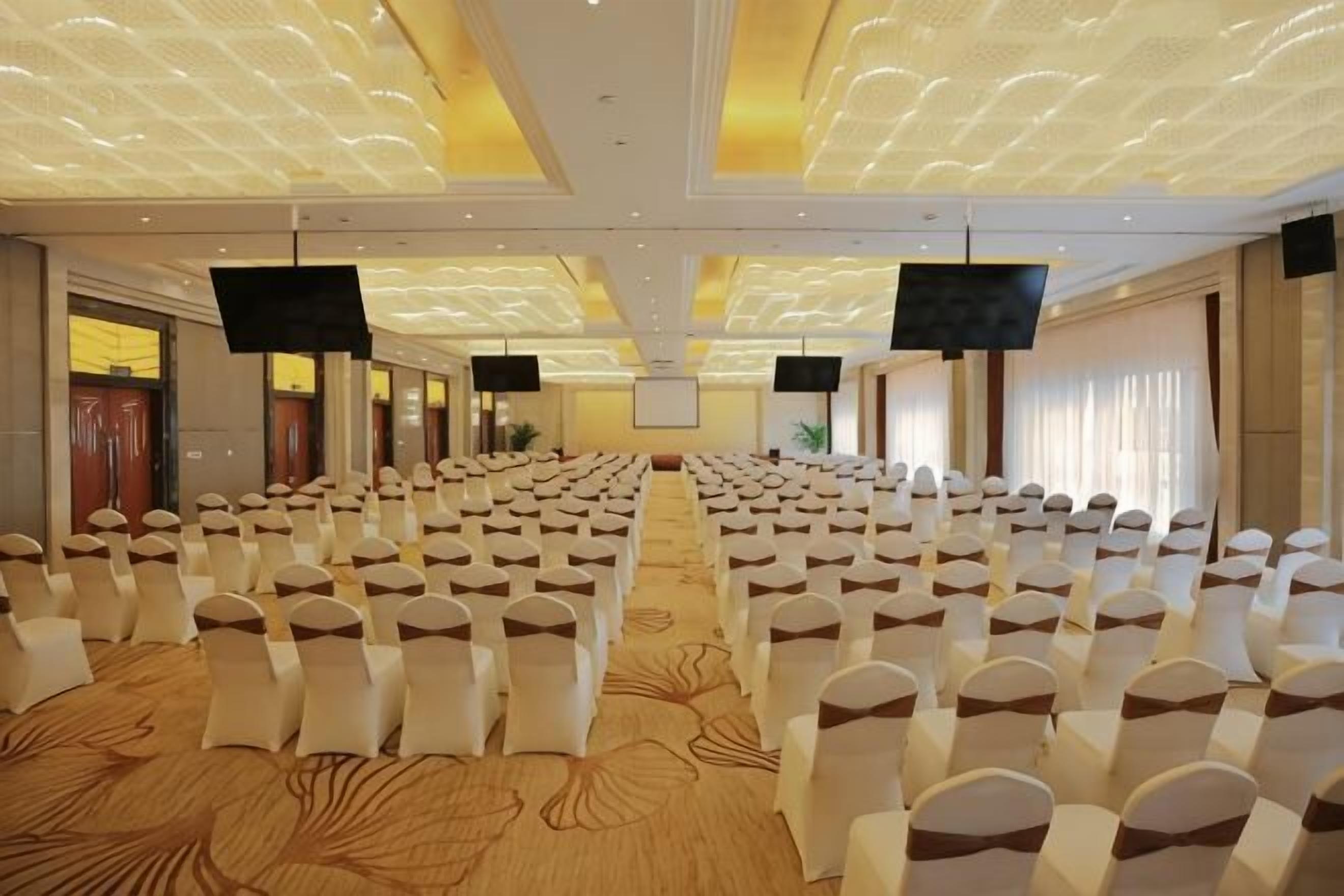A conference room with rows of chairs, a carpeted floor, and a patterned ceiling.