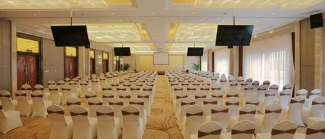 A conference room with rows of chairs, a carpeted floor, and a patterned ceiling.