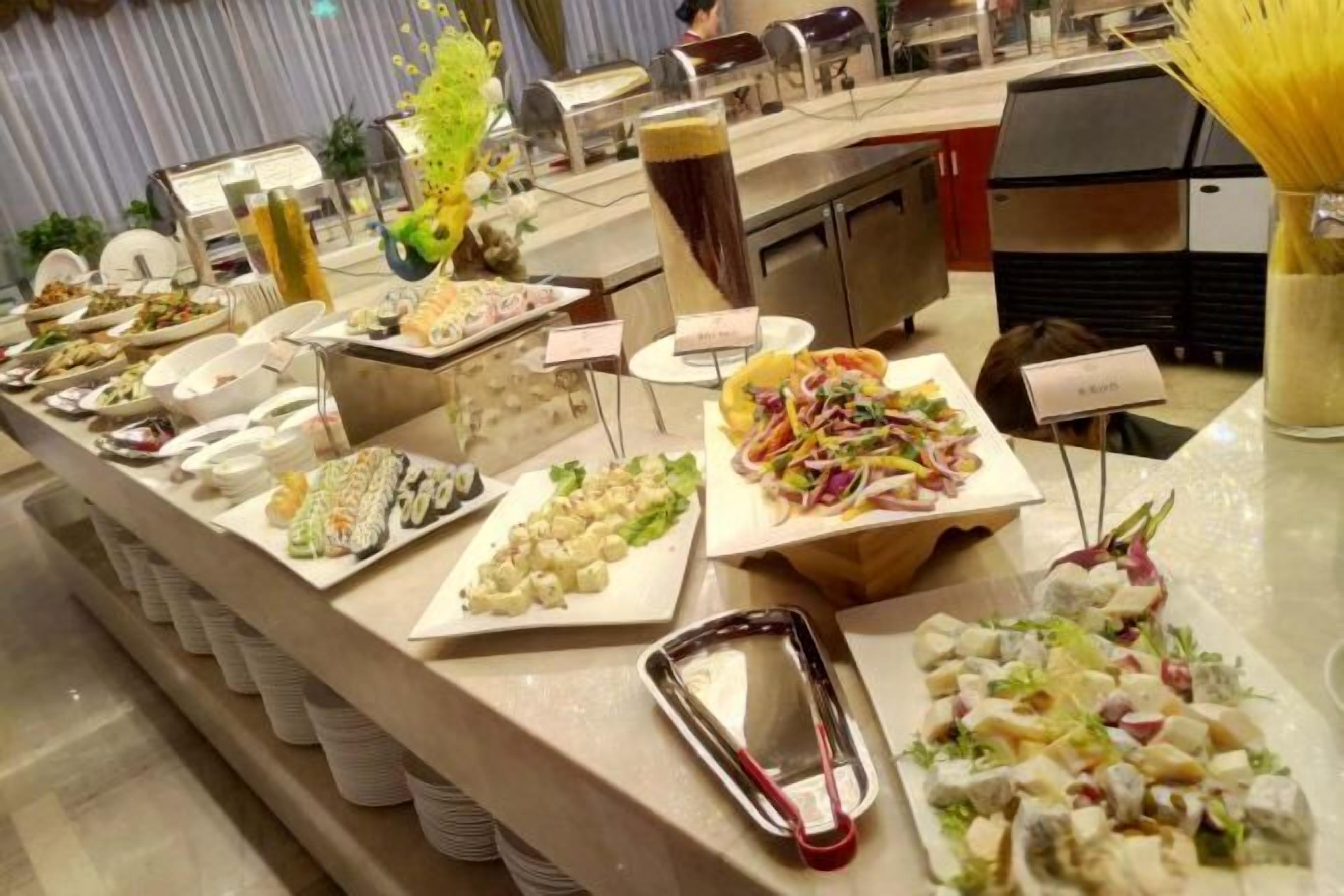 Un buffet proposant une variété de plats, notamment des salades, des pâtes et d’autres amuse-gueules.