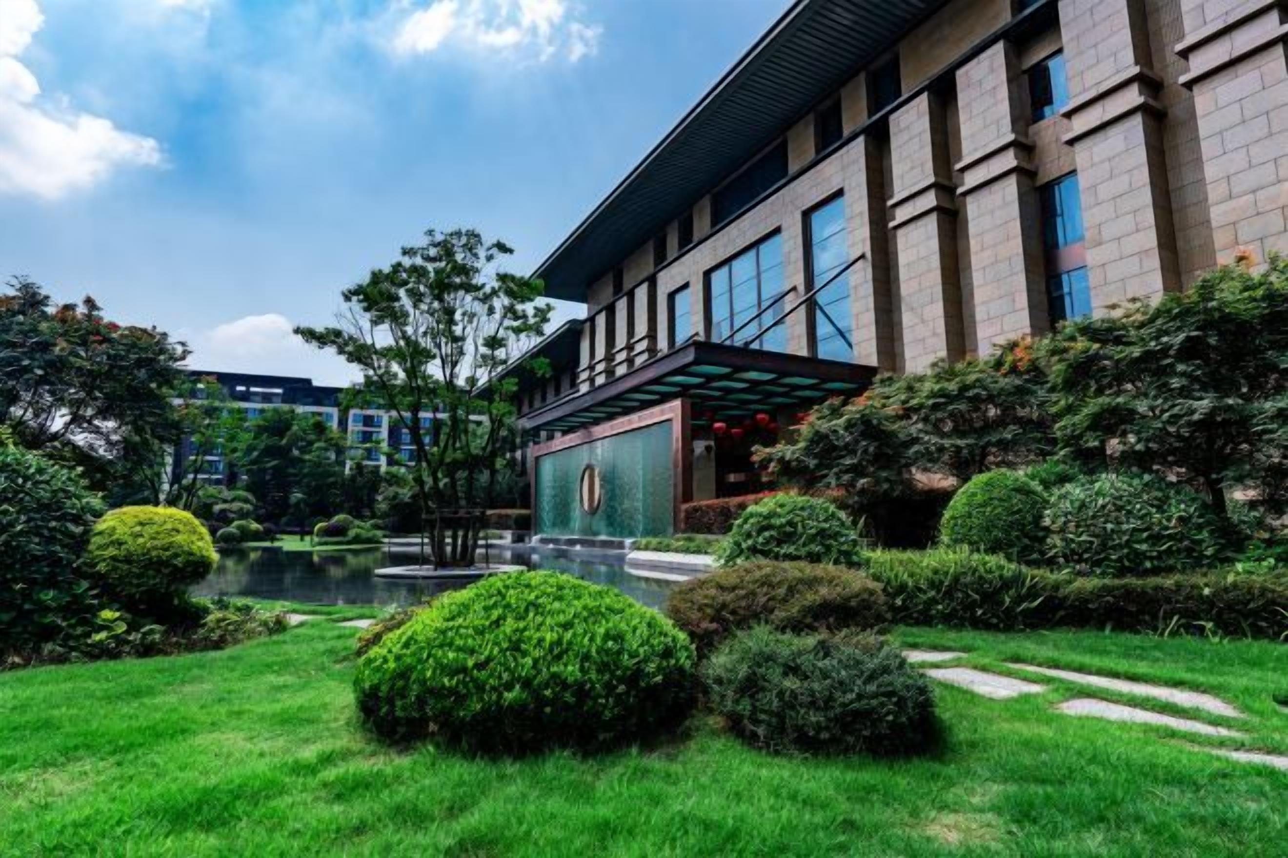 A modern building with a courtyard, a pond, and well-maintained greenery.