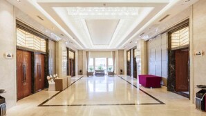 A spacious lobby with a polished marble floor, a central seating area, and a modern ceiling design. - Zhonghe Tianyi Hotel (Dujiangyan)