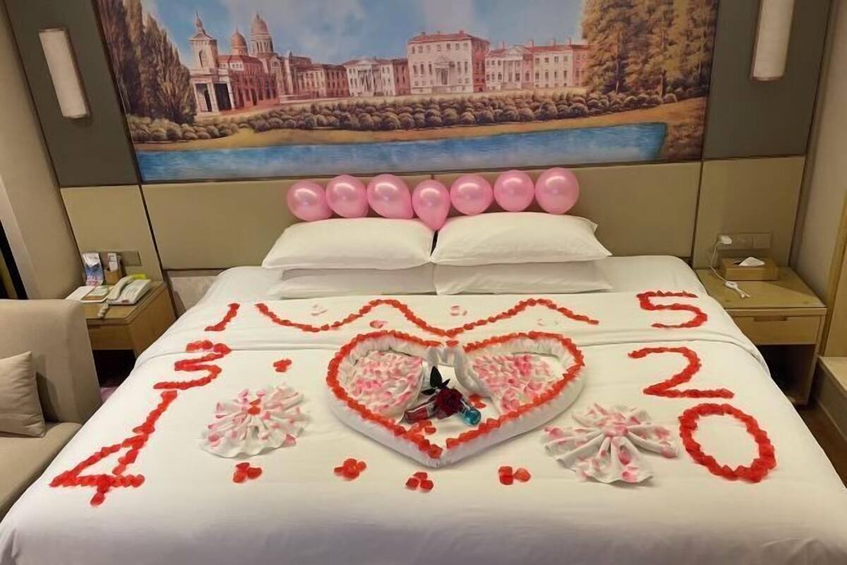 Une chambre d’hôtel avec un lit décoré de pétales de rose et un motif en forme de cœur représentant le chiffre « 520 ».