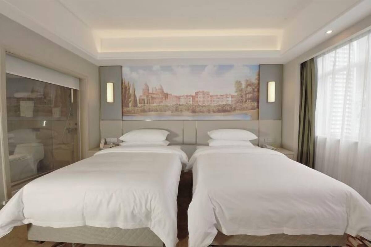 Une chambre d’hôtel avec deux lits, une salle de bain et une grande fenêtre.