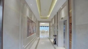 A corridor with a polished floor, framed artwork on the walls, and a ceiling with recessed lighting. - Vienna International Hotel (Bama) (Bama)