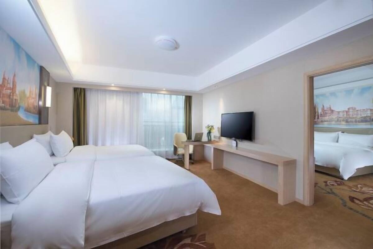 Une chambre d’hôtel avec un lit, un bureau, une télévision et un tableau au mur.