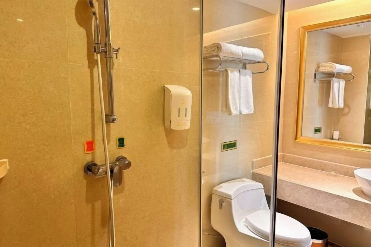 Un baño moderno con ducha envuelta en vidrio, inodoro y tocador con espejo.