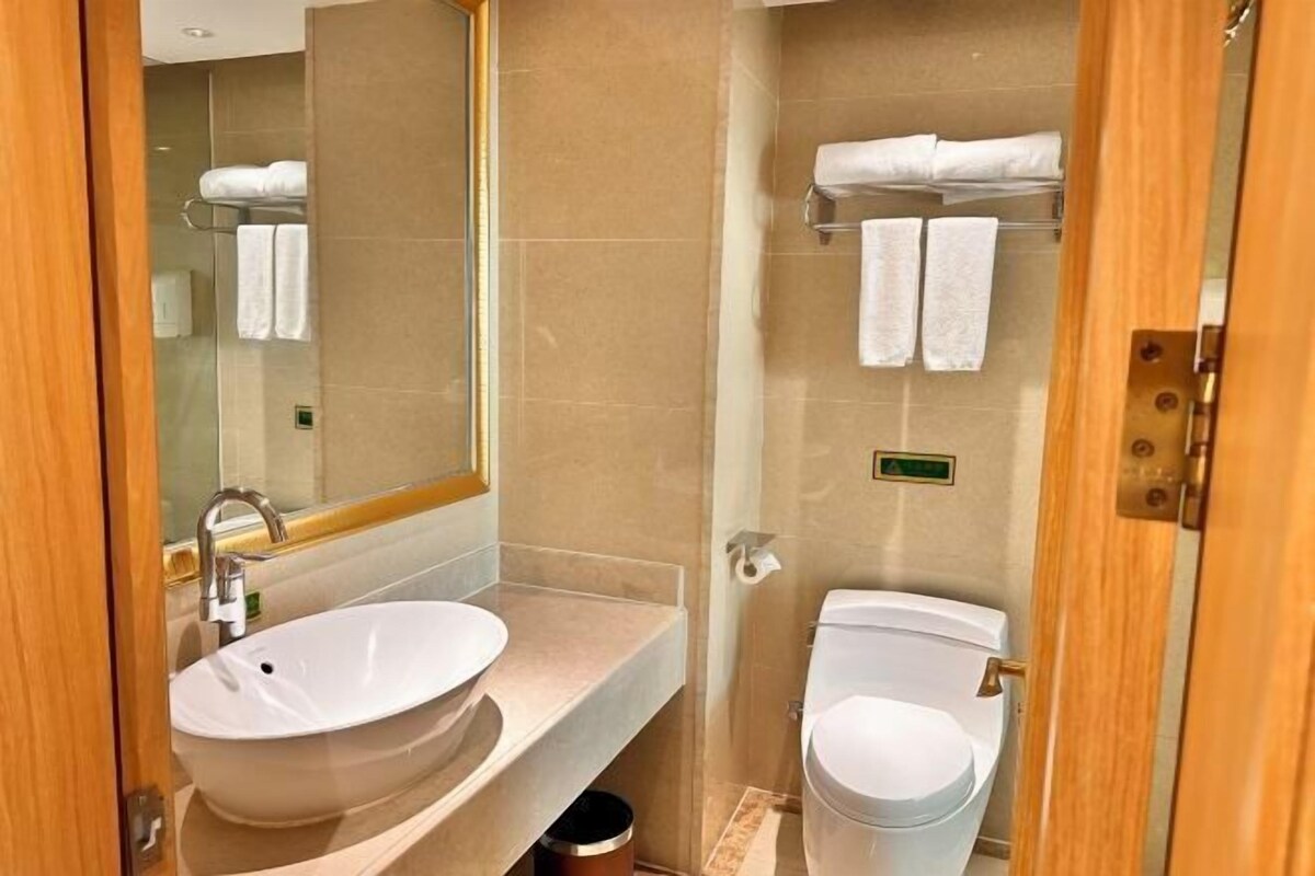 Un baño moderno con lavamanos, espejo y retrete.