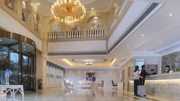 A spacious lobby with a grand chandelier, a reception desk, and a seating area with a sofa. - Vienna International Hotel (Bama) (Bama)
