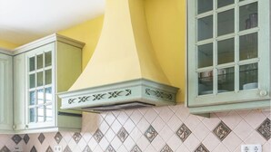 Uma cozinha com armários verdes, parede amarela e painel de azulejos.