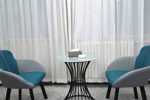 A room with two chairs, a small round table, and a white curtain. - Hantang Tianrun Hotel (Weihai)