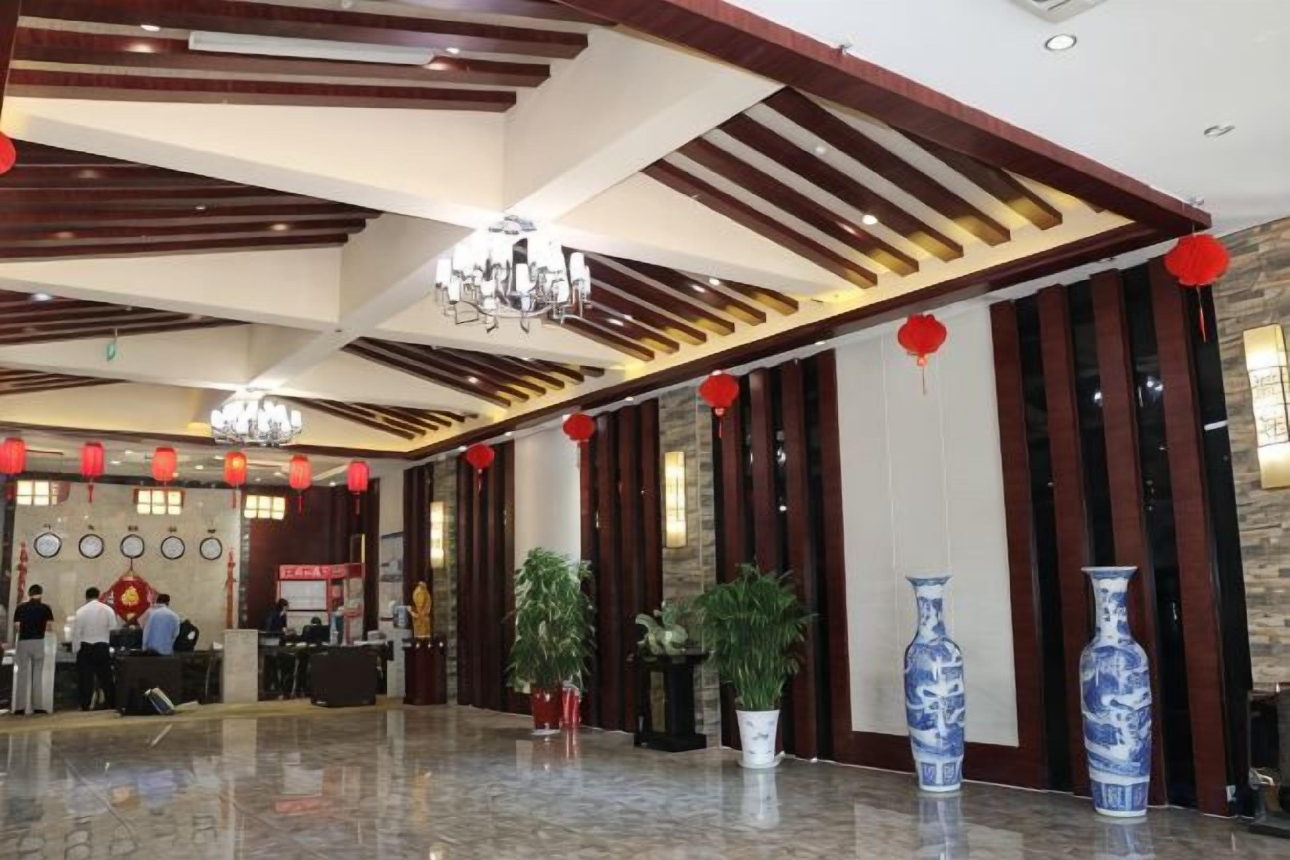 A hotel lobby with a reception desk, potted plants, and decorative vases.