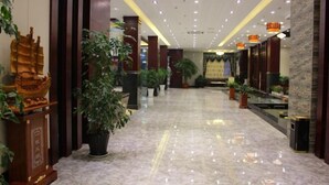 Un vestíbulo de hotel con piso de mármol, plantas en macetas y decoración tradicional.