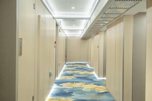 A narrow hallway with a patterned carpet, doors on both sides, and a ceiling with recessed lighting. - Hantang Tianrun Hotel (Weihai)