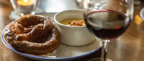 A plate with a pastry, a small bowl of soup, and a glass of red wine on a table.