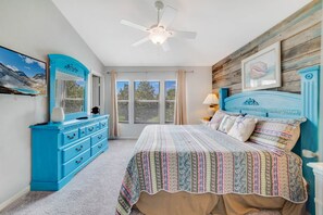 A bedroom with a bed, a dresser, a ceiling fan, and a window with blinds.