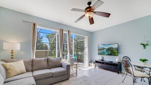 A spacious living room with a sofa, TV, and dining area. - End Unit Magical Retreat (Four Corners)