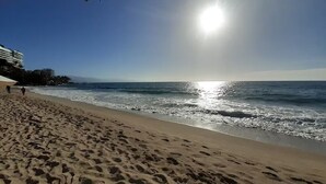 A beach with footprints in the sand, a clear sky, and the ocean in the background. - Le Petit Coeur • Beautiful Ocean View Romantic Zone (Puerto Vallarta)