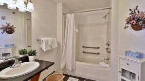 Een badkamer met een wastafel, spiegel, douche en handdoekrek.