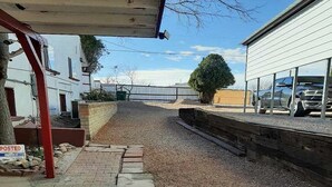 A gravel driveway leading to a building with a covered area and a parked car.