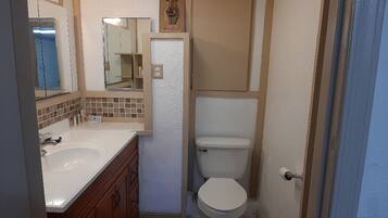Un baño con lavamanos, espejo e inodoro blancos.