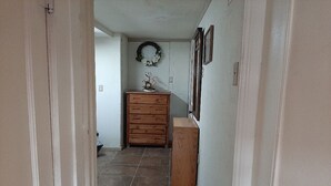 A narrow hallway with a wooden dresser and a small table with a vase.