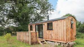 Una cabaña de madera con puerta, ventanas y un porche pequeño.