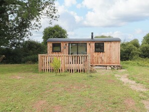 A wooden cabin with a fenced deck, large windows, and a chimney. - The Honeybee (Pembroke)