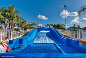 Eine Wasserrutsche im Solara Resort, mit einer blauen Rutsche und einem Schild mit der Aufschrift 'FLOWRIDER'.