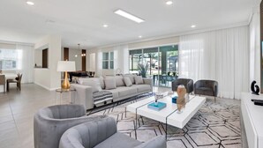 A modern living room with a sofa, armchairs, a coffee table, and a pool table. - Exclusive Estate on Mermaid Cove 6274 (Kissimmee)