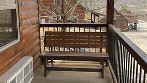 A wooden cabin with a bench on a covered porch.