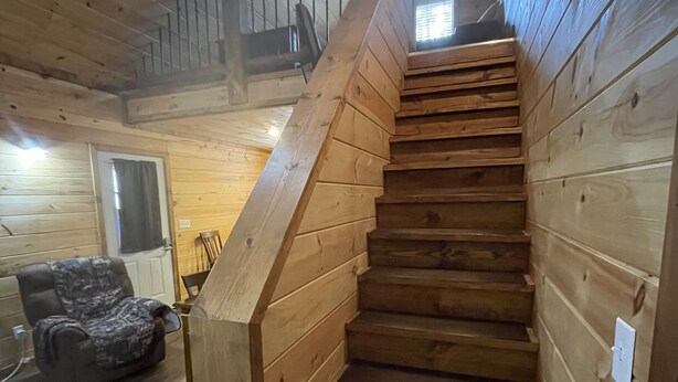 A wooden staircase with a handrail leading to an upper level.