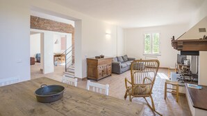 A spacious living area with a dining table, a sofa, and a wooden rocking chair.